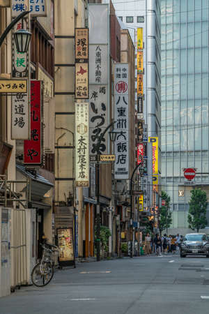 Tokyo, Chuo Ward - August 26, 2018 : People walking along Nihonbashi streets full of colorful billboards, restauranst and shops. Skyscraper in the backgroundのeditorial素材