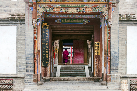 CHINA, XINING - SEPTEMBER 15, 2018. Monk Is Walking Into The Tibetan Temple. Man Is Entering In Old The Buddhist Kumbum Monastery.のeditorial素材