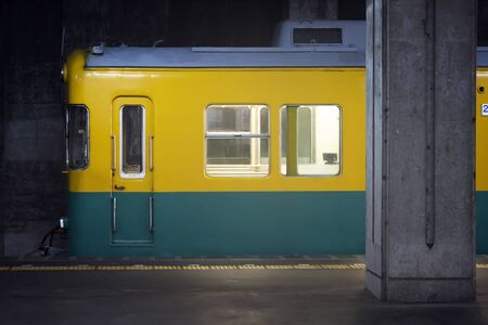 The Train Has Arrived To The Railway Station. Yellow - Blue Green Coach Of Head Of Train, Windows and A Door And Platform.の写真素材