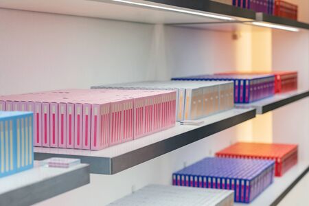 Full Shelf of Colorful Boxes. Pile of Cardboard Boxes. Display of Row Blue, Yellow and Pink Boxes.の写真素材