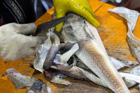 Person Cleaning Fish by Sharp Knife in Seafood Market. Chopping and Peeling off Fish Skin.の写真素材