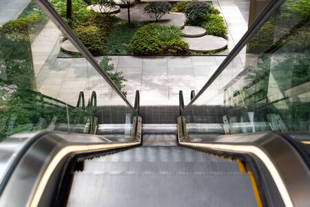 Escalator Going Down to the Green Sunken Plaza. Well Landscaped Courtyard. Technology and Nature.の写真素材