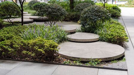 Round Concrete Steps in the Small Garden. Pathway Between Bushes and Trees. Landscape Design of Sustainable Green Architecture. Stepping Stones at Greenery.の写真素材