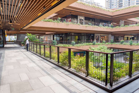 SHANGHAI, CHINA - NOVEMBER 10, 2018. Ruihong Tiandi Shopping Mall. External Courtyard of a Retail Complex with Lush Greenery. Garden with Footbridge and Terraces. Green Sustainable Architecture.のeditorial素材
