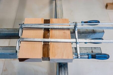 Three Wooden Bars are Glued to Each Other at Woodwork. Wood Pieces Fixed by Jaws Vise Tongs.の写真素材