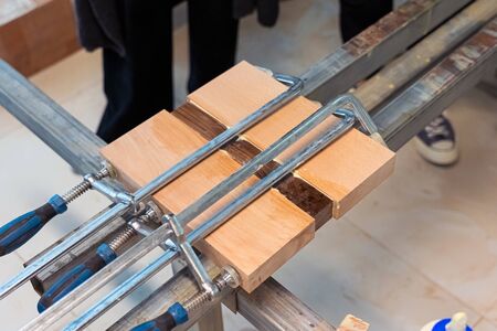 Three Wooden Bars are Glued to Each Other at Woodwork. Wood Pieces Fixed by Jaws Vise Tongs.の写真素材