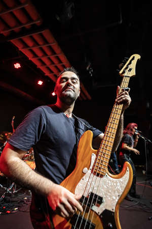 Caucasian Man is Performing on the Stage with Band. Handsome Male Person is Playing on Bass Guitar...