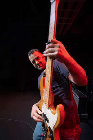 Caucasian Man is Performing on the Stage. Handsome Male Person is Playing on Bass Guitar at Concert.の写真素材