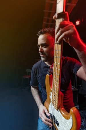 Caucasian Man is Performing on the Stage. Handsome Male Person is Playing on Bass Guitar at Concert.