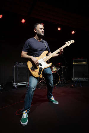 Caucasian Man is Performing on the Stage. Handsome Male Person is Playing on Bass Guitar at Concert.の写真素材