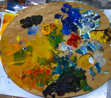 Palette with a colorful mix of different colors. Wooden palette with paints that are poured on it to blend into the color you wantの写真素材