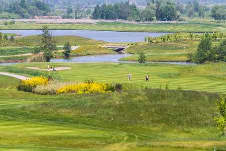Golf Course - forvey, bushes, green grass track. People playing golf.の写真素材