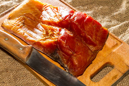 Smoked fish,wooden board, knife, burlap.の写真素材