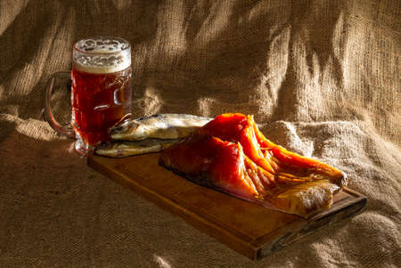 Smoked fish, dried fish, wooden board, beer, burlap.の写真素材
