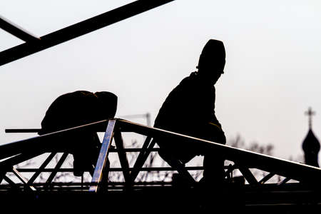 Workers builders high-builders build a roof at the height of the domes of the church. Black and white photo. Silhouettes and
Contoursの写真素材