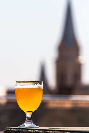 A glass of unfiltered beer looks gorgeous against the background of the old buildings of the beautiful city of Mukacheve, Ukraineの写真素材