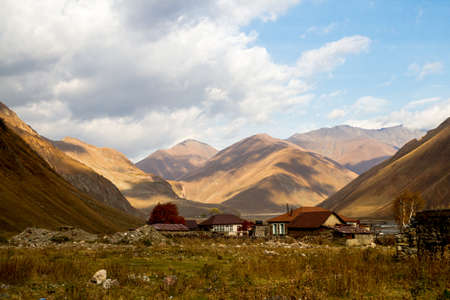 Mountains of the Caucasus, gorges, clouds, a narrow road, high mountains, flocks of sheep, old houses along the road, passes and the play of light and shadow - all this is the military-Georgian road.の写真素材