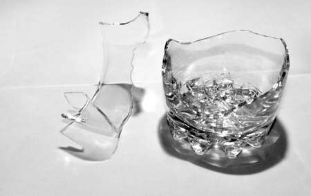 A broken whiskey glass with splinters stands on a white background.の写真素材
