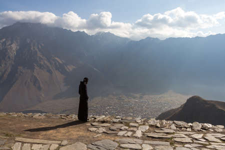 A monk from the monastery on top of a mountain looking at the valley belowの写真素材