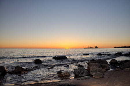 Sea at sunset far away can be seen the silhouette of the ship.の写真素材