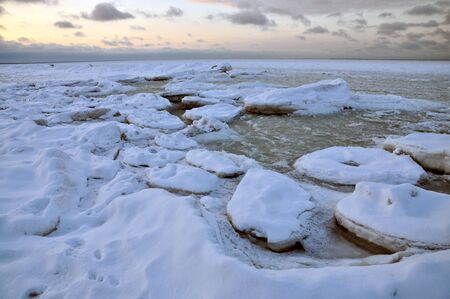Frozen seascape with colorful clouds at sunset.の写真素材