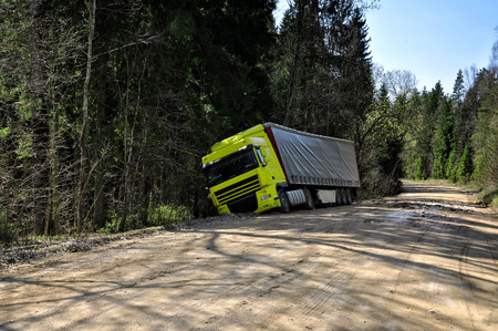 Yellow truck crashed to the forest road.の写真素材