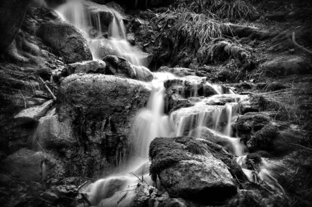 Sources with ferrous impurities flowing over large stones.の写真素材