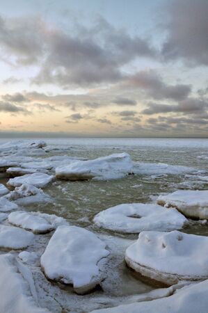 Frozen seascape with colorful clouds at sunset.の写真素材