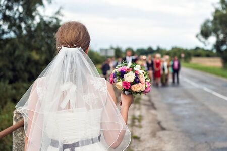 Bride with bridal bouquet in the hands of the groom expect.の写真素材
