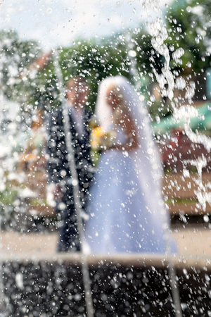 Behind the water fountain seen the groom and the bride.の写真素材