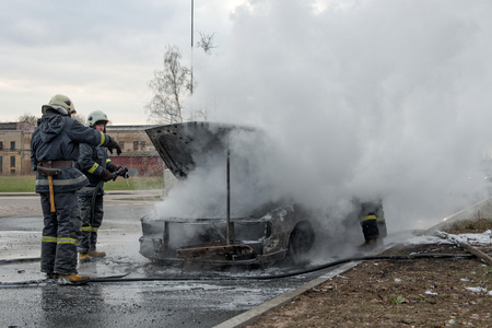 RIGA, LATVIA - APRIL 11, 2014: A few minutes in the street burnt car. Traffic is stopped. Firefighters eliminate fire.のeditorial素材