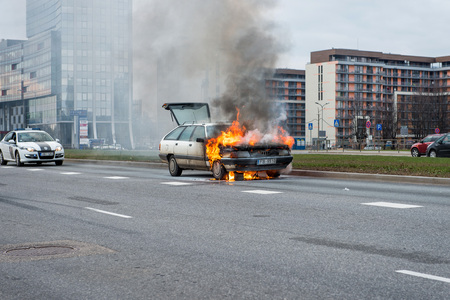 RIGA, LATVIA - APRIL 11, 2014: A few minutes in the street burnt car. Traffic is stopped. Firefighters eliminate fire.のeditorial素材