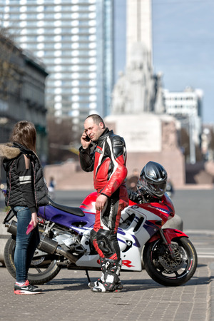 RIGA, LATVIA - APRIL 22, 2015: Unknown man on the street to bike talking on the phone.のeditorial素材