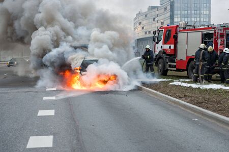 RIGA, LATVIA - APRIL 11, 2014: A few minutes in the street burnt car. Traffic is stopped. Firefighters eliminate fire.のeditorial素材