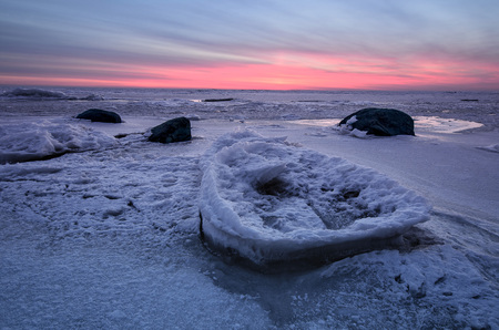 Abstract frozen winter sunrise seascape with ice and colored the sky.