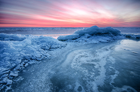 Abstract frozen winter sunrise seascape with ice and colored the sky.の写真素材