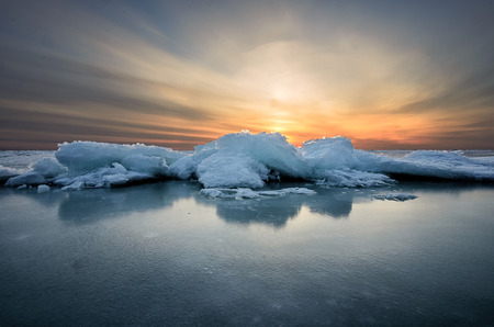 Abstract frozen winter sunrise seascape with ice and colored the sky.の写真素材
