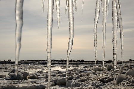Cold winter landscape with frozen sea coast, ice and icicles.の写真素材