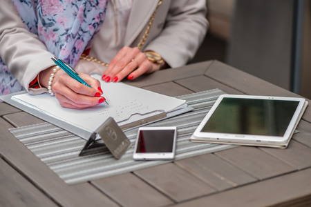 Close-up of female hands. Woman writing something sitting at cafe. Signing documents.の写真素材