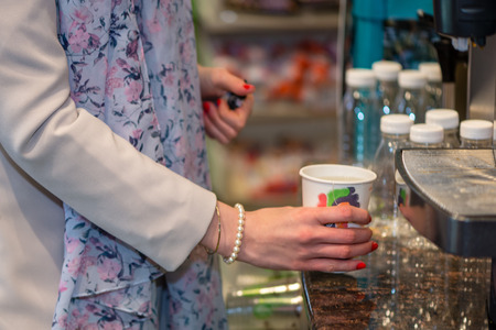 Close up photography. Women's hands hold a colored paper glass with a hot drink.の写真素材