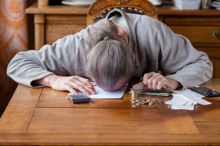 Close up man with calculator counting, making notes at home, hand is writes in a notebook. Stacked coins arranged at deesk. Savings finances concept. Businessman in panic. Stress at work.の写真素材