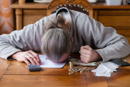 Close up man with calculator counting, making notes at home, hand is writes in a notebook. Stacked coins arranged at deesk. Savings finances concept. Businessman in panic. Stress at work.の写真素材
