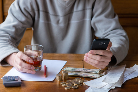 Close up man with calculator counting, making notes at home, hand is writes in a notebook. Stacked coins arranged at deesk. Savings finances concept.の写真素材