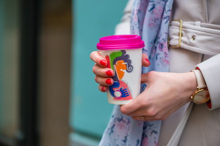 Women's hands hold a paper cup of hot tea.の写真素材