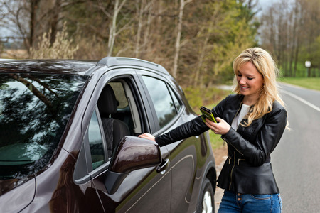 young attractive desperate and confused woman standing next to her car and talking to mobile phoneの写真素材