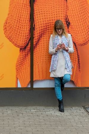 A young business woman in the city on the street reads messages on the phone.の写真素材