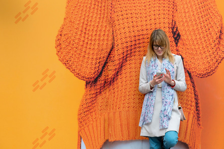 A young business woman in the city on the street reads messages on the phone.の写真素材