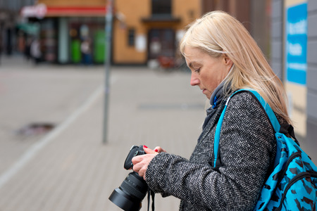 Blonde photographer watched photos in the camera.の写真素材