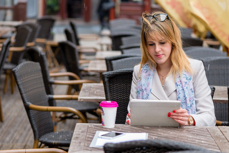 A young business woman drinking tea in a cafe and working with a computer. の写真素材