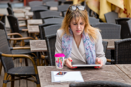 A young business woman drinking tea in a cafe and working with a computer. の写真素材